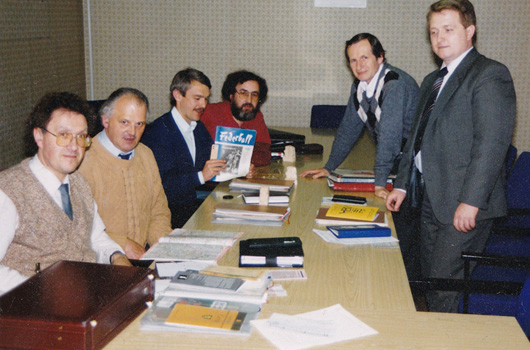 Die historische Aufnahme zeigt einen Erfahrungsaustausch von Vertretern aus Thüringen und Hessen. Zu sehen sind auf der linken Seite des Tisches v.v.n.h. Dieter Fachinger (Hessen), Gerhard Hopp (Suhl), Walter Pabst (Hessen) und Wolfgang Enders (Hessen). Auf der rechten Seite des Tisches v.v.n.h. Volkmar Burgold (Gera) und Klaus Peine (Ilmenau).